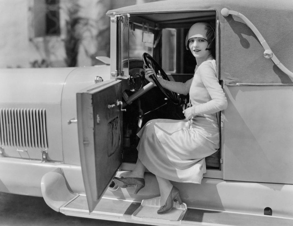 Femme à l'avant d'une voiture ancienne