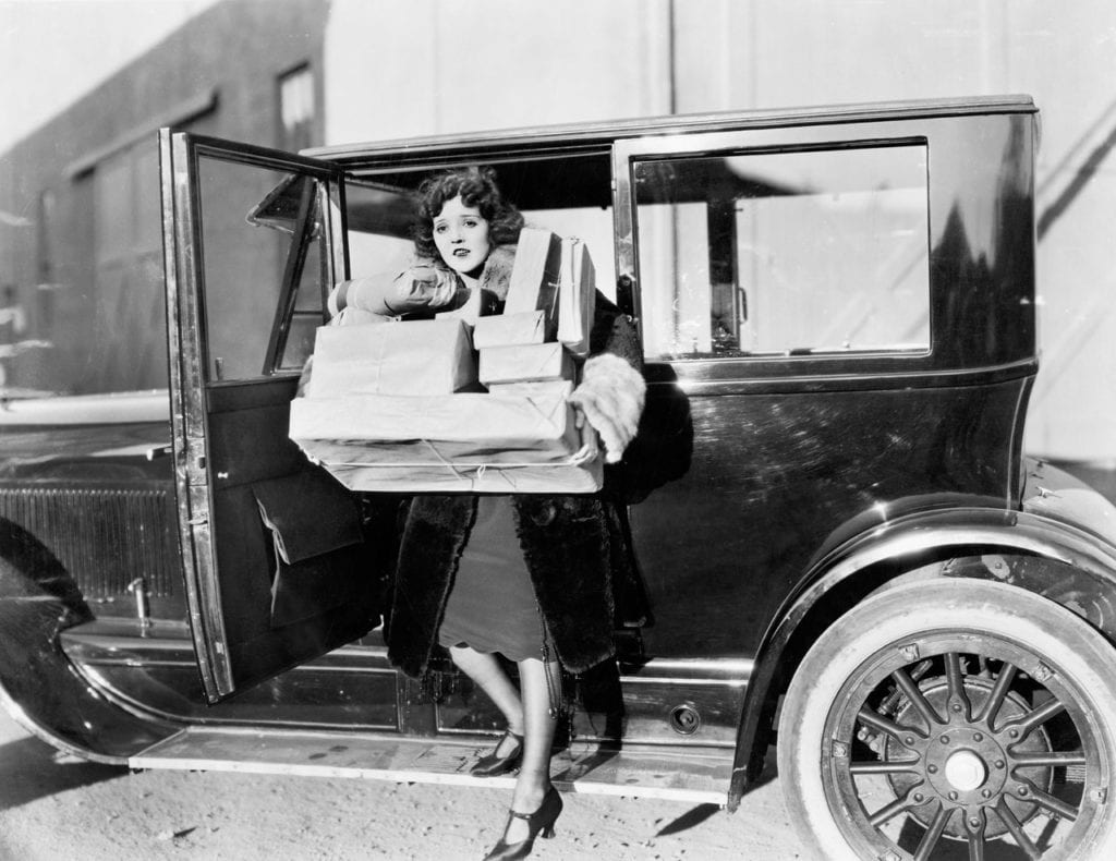 Femme portant des paquets sortant d'une voiture ancienne