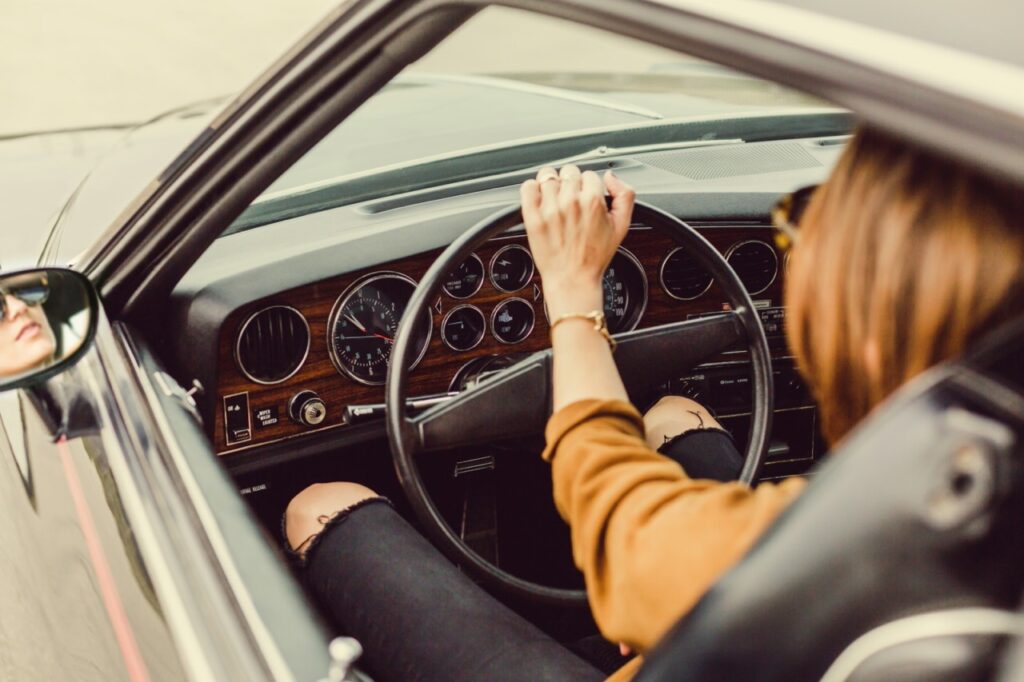 Femme au volant d'une voiture classique