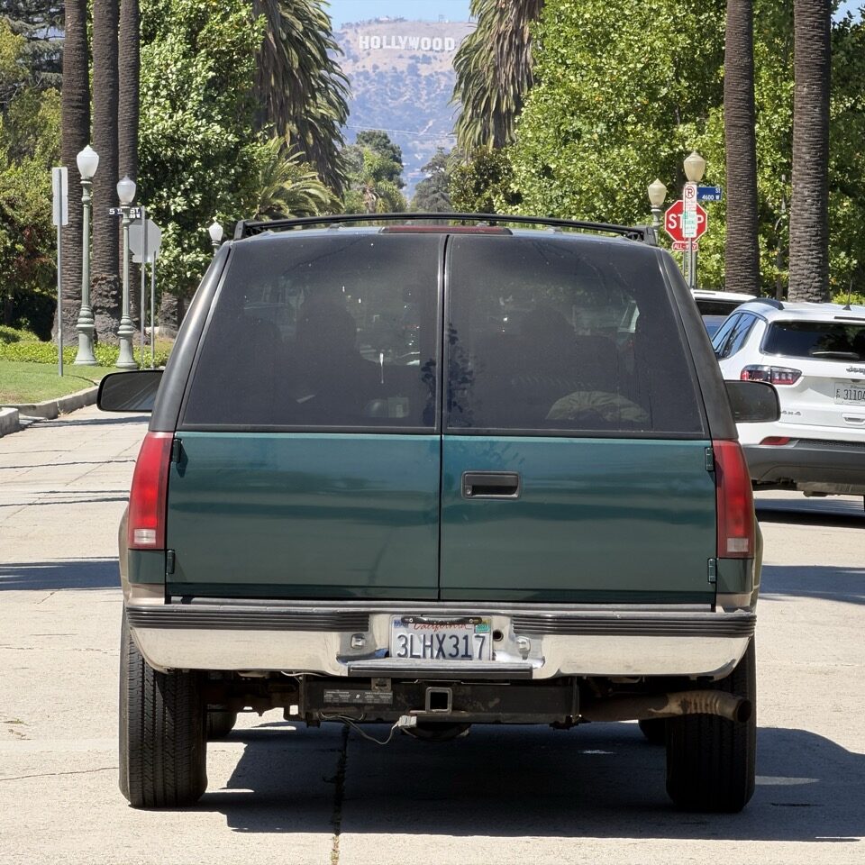 Le Suburban 1995 vu de dos face au panneau Hollywood à Los Angeles