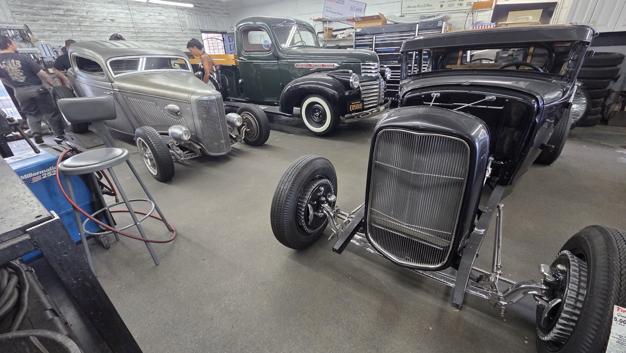 Vue d'ensemble de l'atelier Hollywood Hot Rods avec trois véhicules en cours de construction