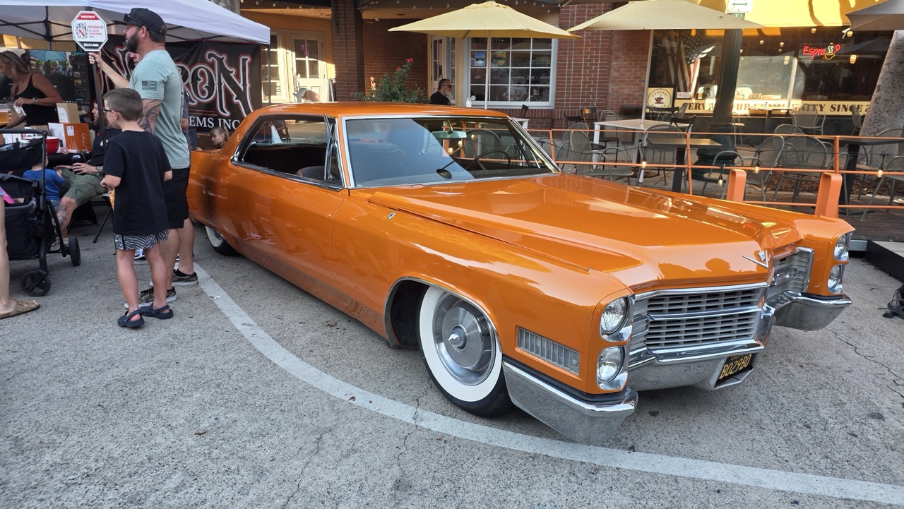 Cadillac Coupe de Ville 1966 orange surbaissée exposée dans une rue de Glendora
