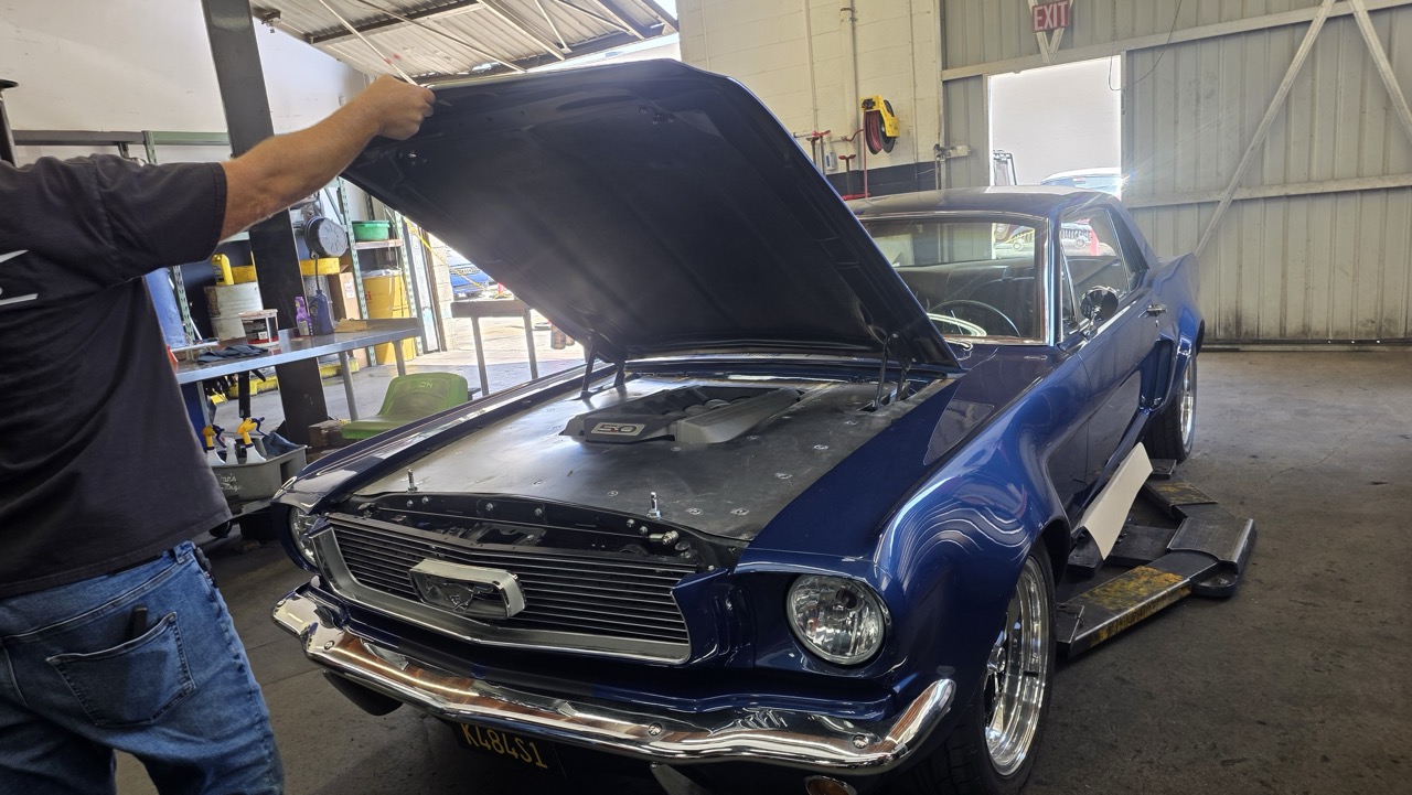Ford Mustang 1966 restomod capot ouvert, moteur Ford Coyote 5.0, sur un pont d'atelier